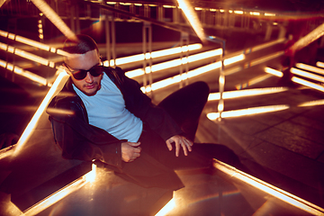 Image showing Cinematic portrait of handsome young man in neon lighted room, stylish musician