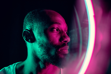 Image showing Cinematic portrait of handsome young man in neon lighted room, stylish musician