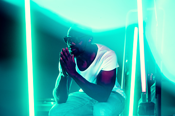 Image showing Cinematic portrait of handsome young man in neon lighted room, stylish musician