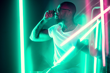 Image showing Cinematic portrait of handsome young man in neon lighted room, stylish musician