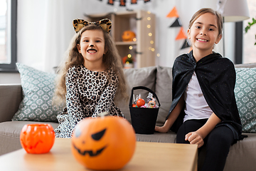 Image showing girls in halloween costumes with candies at home