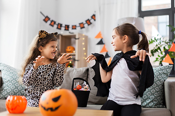 Image showing girls in halloween costumes with candies at home