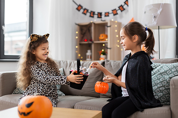Image showing girls in halloween costumes with candies at home