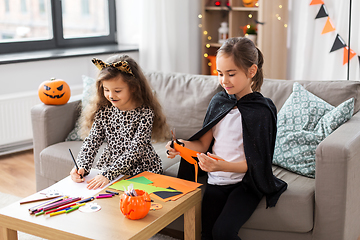 Image showing girls in halloween costumes doing crafts at home