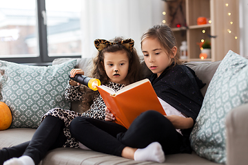 Image showing girls in halloween costumes reading book at home