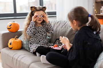 Image showing girls in halloween costumes with candies at home