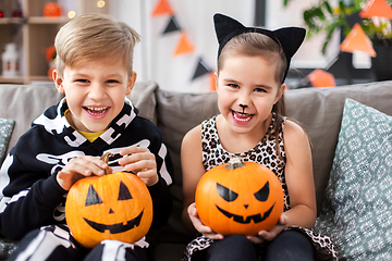 Image showing kids in halloween costumes with pumpkins at home