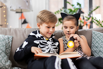 Image showing kids in halloween costumes reading book at home