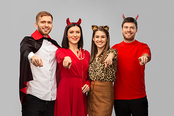Image showing happy friends in halloween costumes over grey