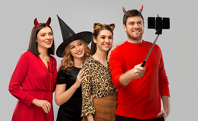 Image showing happy friends in halloween costumes taking selfie