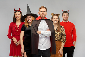 Image showing happy friends in halloween costumes over grey