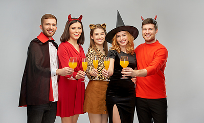 Image showing happy friends in halloween costumes over grey