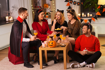 Image showing happy friends in halloween costumes at home party