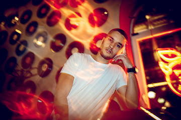 Image showing Cinematic portrait of handsome young man in neon lighted room, stylish musician