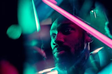 Image showing Cinematic portrait of handsome young man in neon lighted room, stylish musician