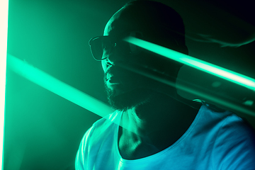 Image showing Cinematic portrait of handsome young man in neon lighted room, stylish musician