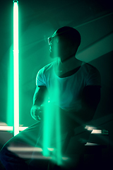 Image showing Cinematic portrait of handsome young man in neon lighted room, stylish musician