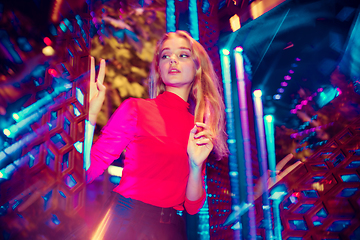 Image showing Cinematic portrait of handsome young woman in neon lighted room, stylish musician