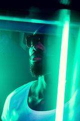 Image showing Cinematic portrait of handsome young man in neon lighted room, stylish musician