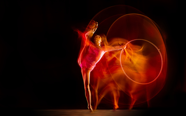 Image showing Young flexible female gymnast isolated on black studio background in mixed light,