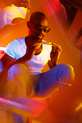 Image showing Cinematic portrait of handsome young man in neon lighted room, stylish musician