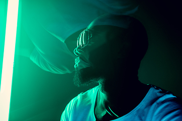 Image showing Cinematic portrait of handsome young man in neon lighted room, stylish musician