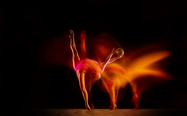 Image showing Young flexible female gymnast isolated on black studio background in mixed light,