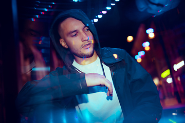 Image showing Cinematic portrait of handsome young man in neon lighted room, stylish musician