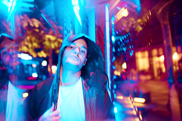 Image showing Cinematic portrait of handsome young man in neon lighted room, stylish musician