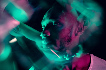 Image showing Cinematic portrait of handsome young man in neon lighted room, stylish musician