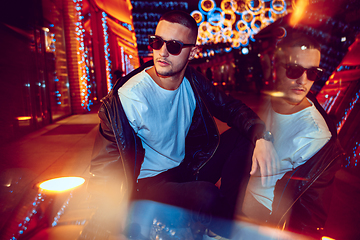 Image showing Cinematic portrait of handsome young man in neon lighted room, stylish musician