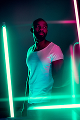 Image showing Cinematic portrait of handsome young man in neon lighted room, stylish musician