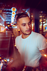 Image showing Cinematic portrait of handsome young man in neon lighted room, stylish musician