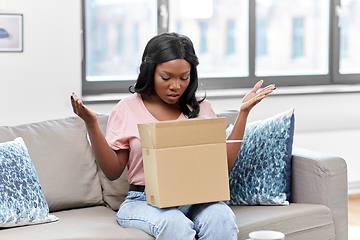 Image showing sad african american woman with parcel box at home