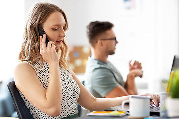 Image showing woman with laptop calling on smartphone at office