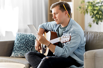 Image showing young man with guitar and music book at home