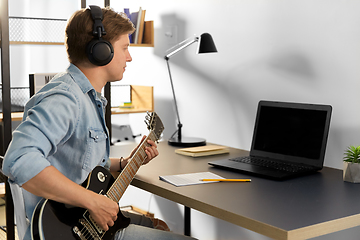 Image showing man in headphones playing bass guitar at home