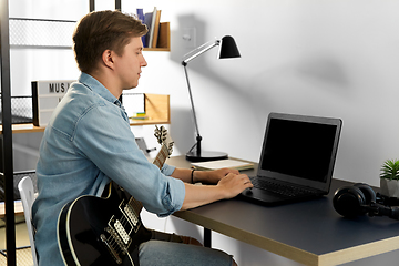 Image showing young man with laptop and bass guitar at home