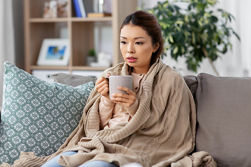 Image showing sad sick asian woman drinking hot tea at home