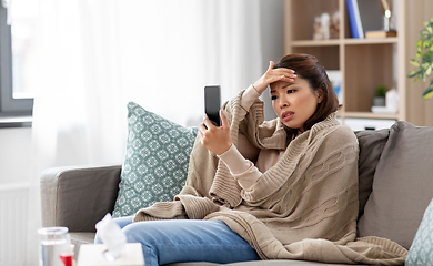 Image showing sick asian woman with smartphone at home