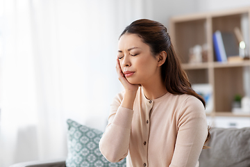 Image showing unhappy woman suffering from toothache at home