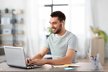 Image showing man with laptop and earphones at home office