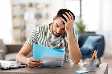 Image showing man with papers and laptop working at home office