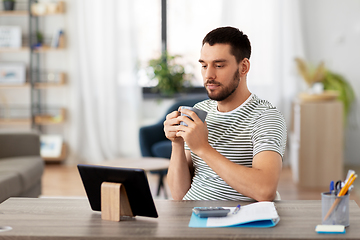Image showing man with tablet pc drinking coffee at home office