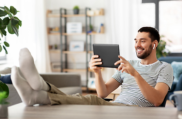 Image showing happy man with tablet pc and earphones at home