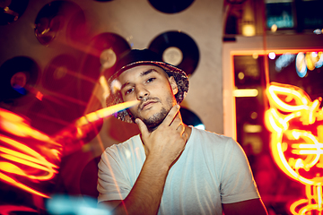 Image showing Cinematic portrait of handsome young man in neon lighted room, stylish musician