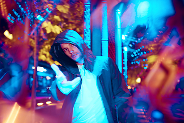 Image showing Cinematic portrait of handsome young man in neon lighted room, stylish musician