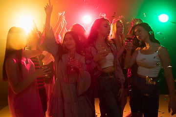 Image showing A crowd of people in silhouette raises their hands on dancefloor on neon light background