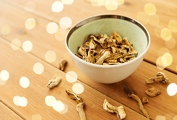 Image showing dried mushrooms in bowl on wooden background