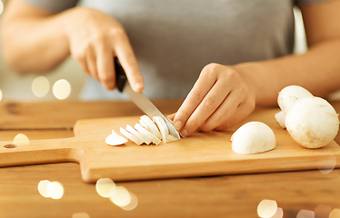 Image showing woman cutting champignons by knife on board